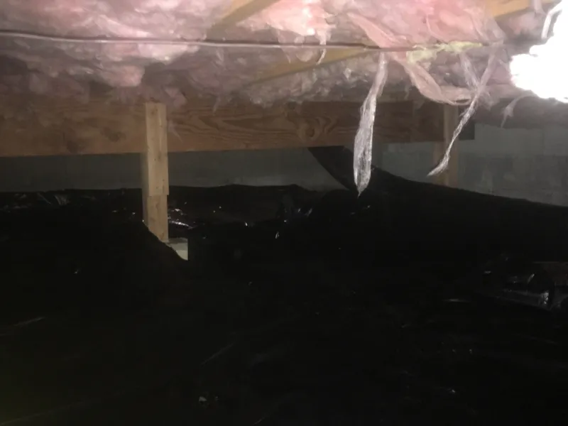 A crawl space with a new plastic vapor barrier on the ground