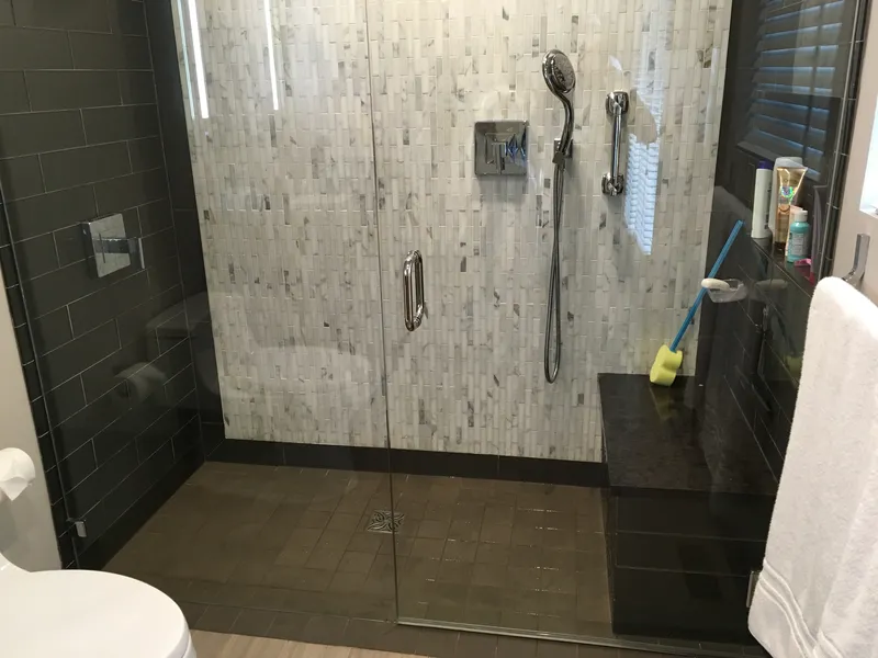 A black and white tile job in a glass walk in shower