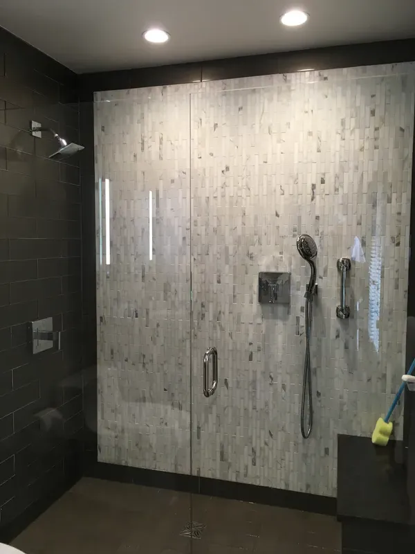 A black and white tile job in a glass walk in shower