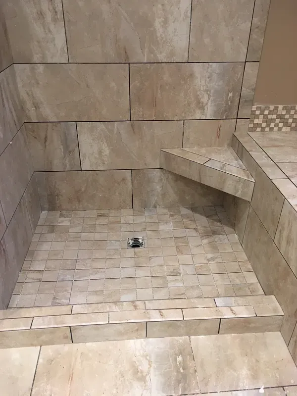 Closeup of the floor of a walk in shower with added stone seat