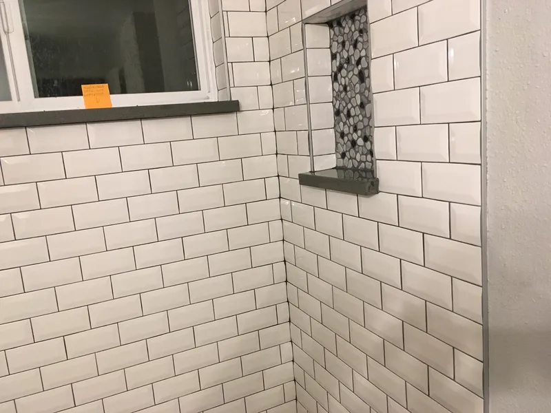 Closeup of a bright white tile pattern and unique soap shelf