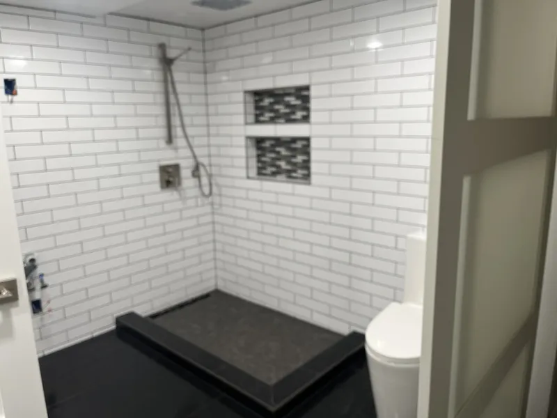 View of a completely redone bathroom with tile walls, shelves, and walk in shower