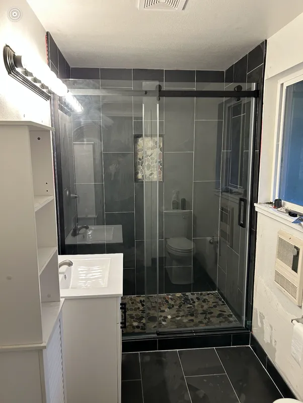 Black tile with glass rolling shower doors