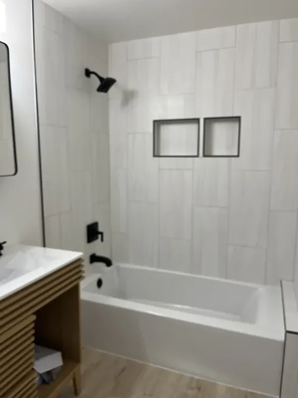 All white tile shower and tub with updated soap shelves